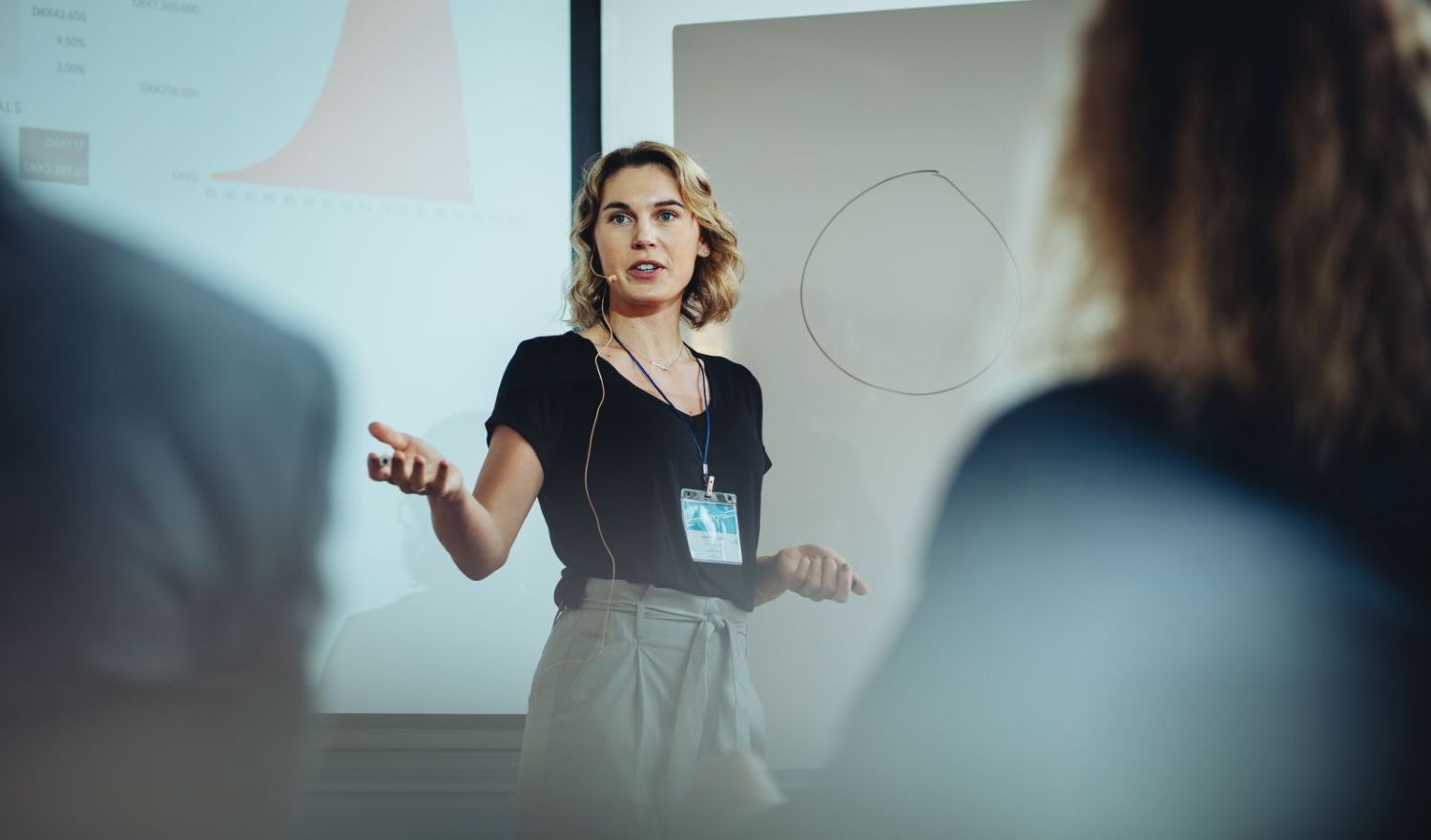 A young woman wearing a headset microphone presents to a class